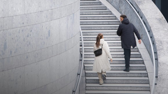 Dos personas subiendo por unas escaleras de cemento en un paisaje urbano.