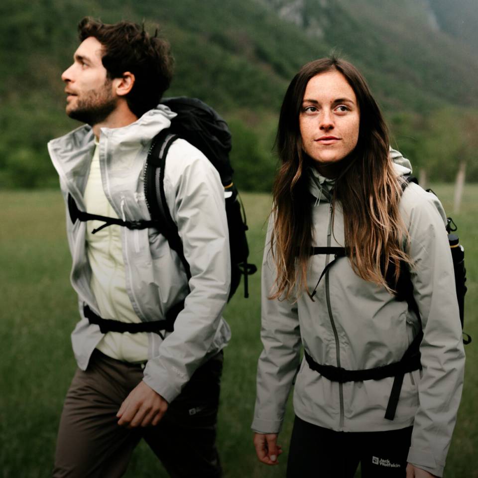 Woman and man in sporty hiking clothing in a green mountain landscape